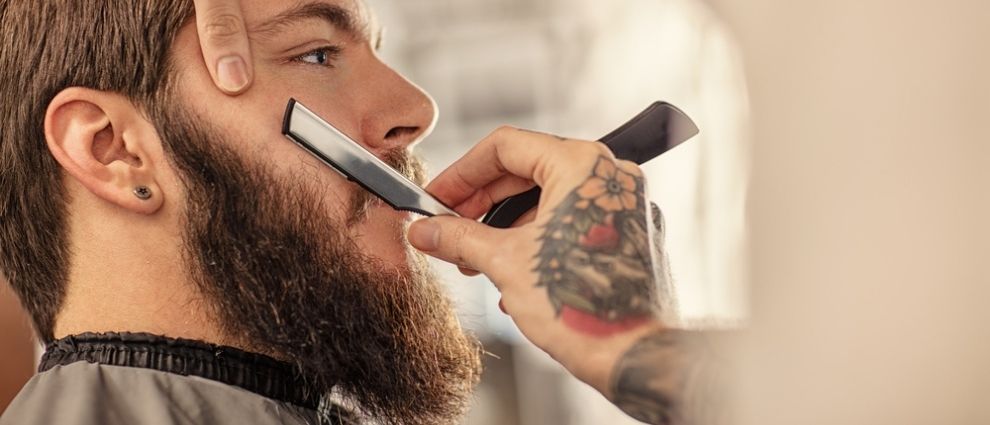 Barbeiro fazendo a barba de seu cliente.